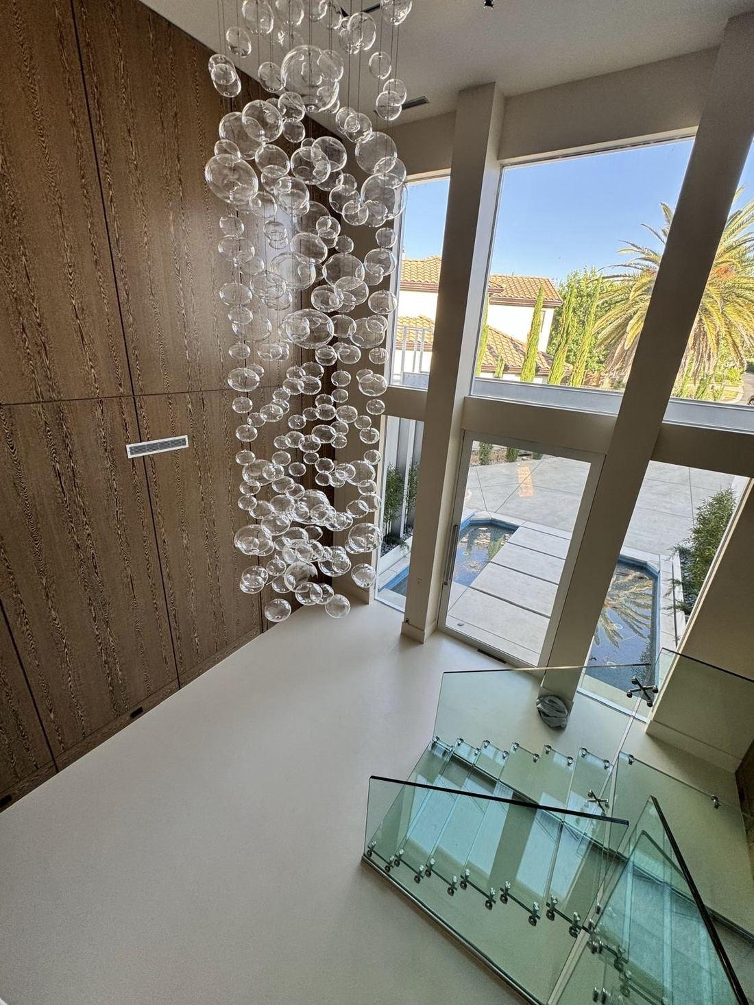 Seamless microcement floor in a double-height entry with glass staircase, Gold Country, Northern California