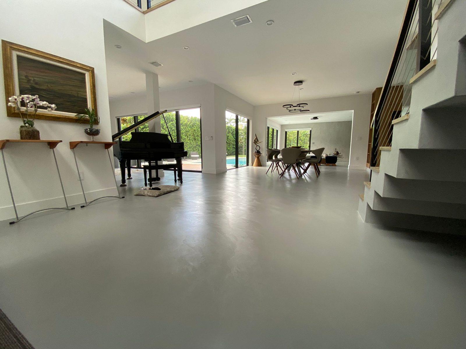 Seamless microcement floor in a Coral Gables living area, running continuously toward the pool terrace