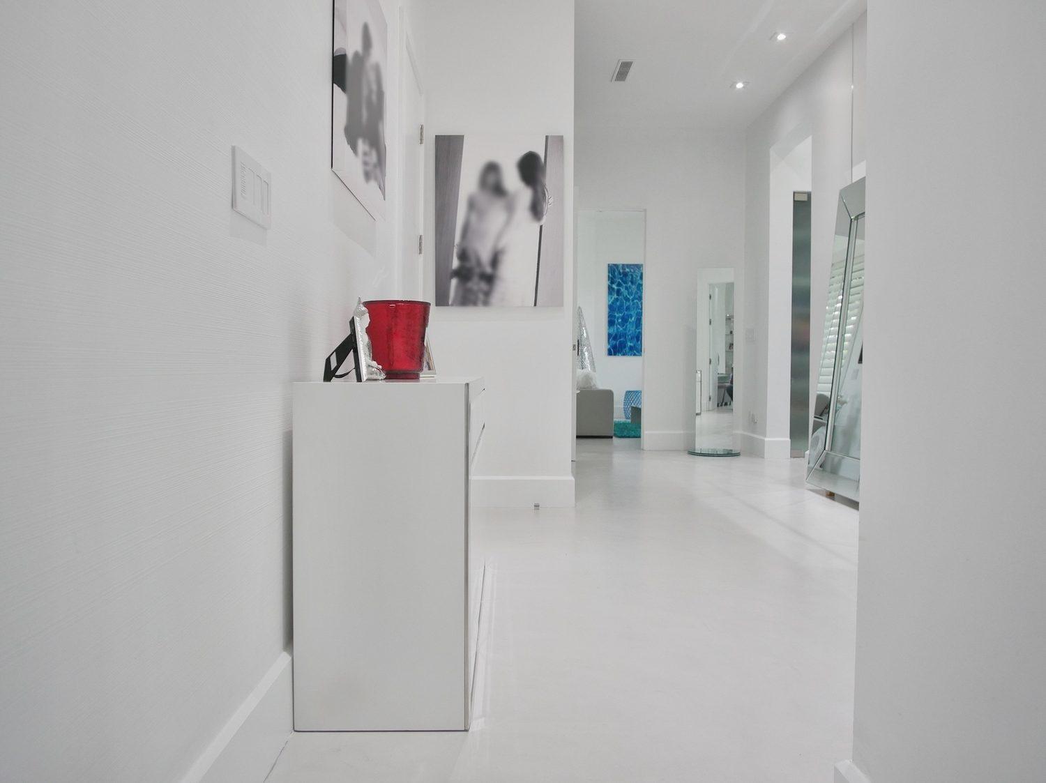 Continuous white microcement floor running through a hallway and living area in an Avalon residence, New Jersey