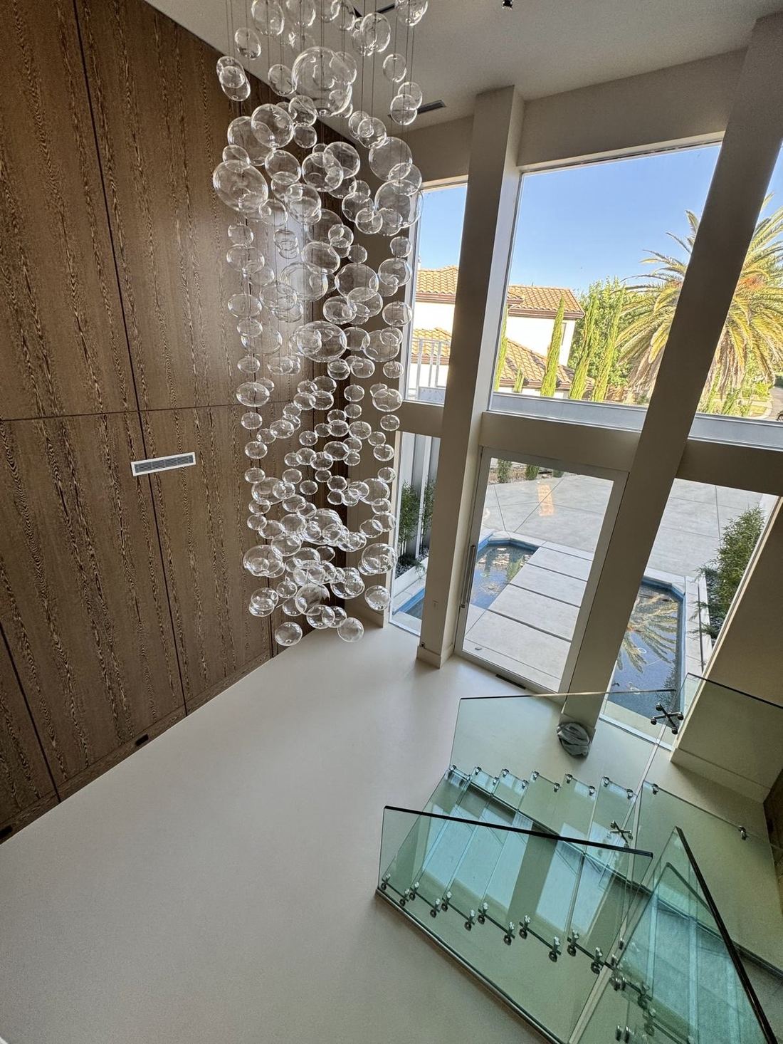 Seamless microcement floor in a double-height entry with glass staircase, Gold Country, Northern California