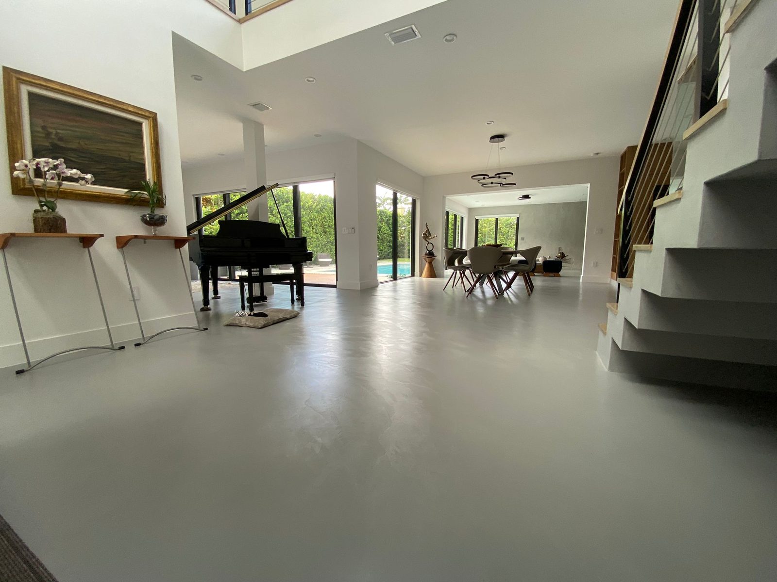Seamless microcement floor in a Coral Gables living area, running continuously toward the pool terrace