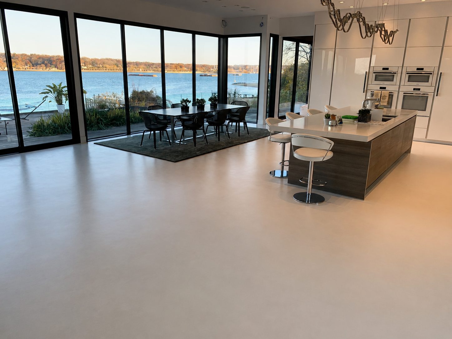 Seamless microcement floor in a waterfront kitchen and dining area in Sands Point, Long Island, New York