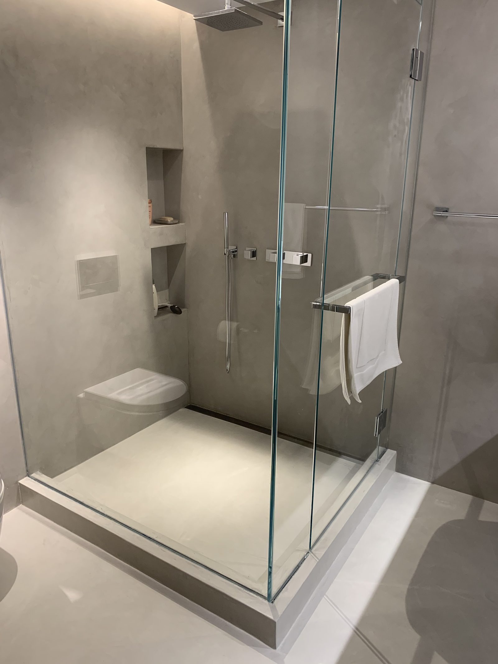 Microcement walk-in shower with seamless walls, niches and shower tray in a Manhattan apartment