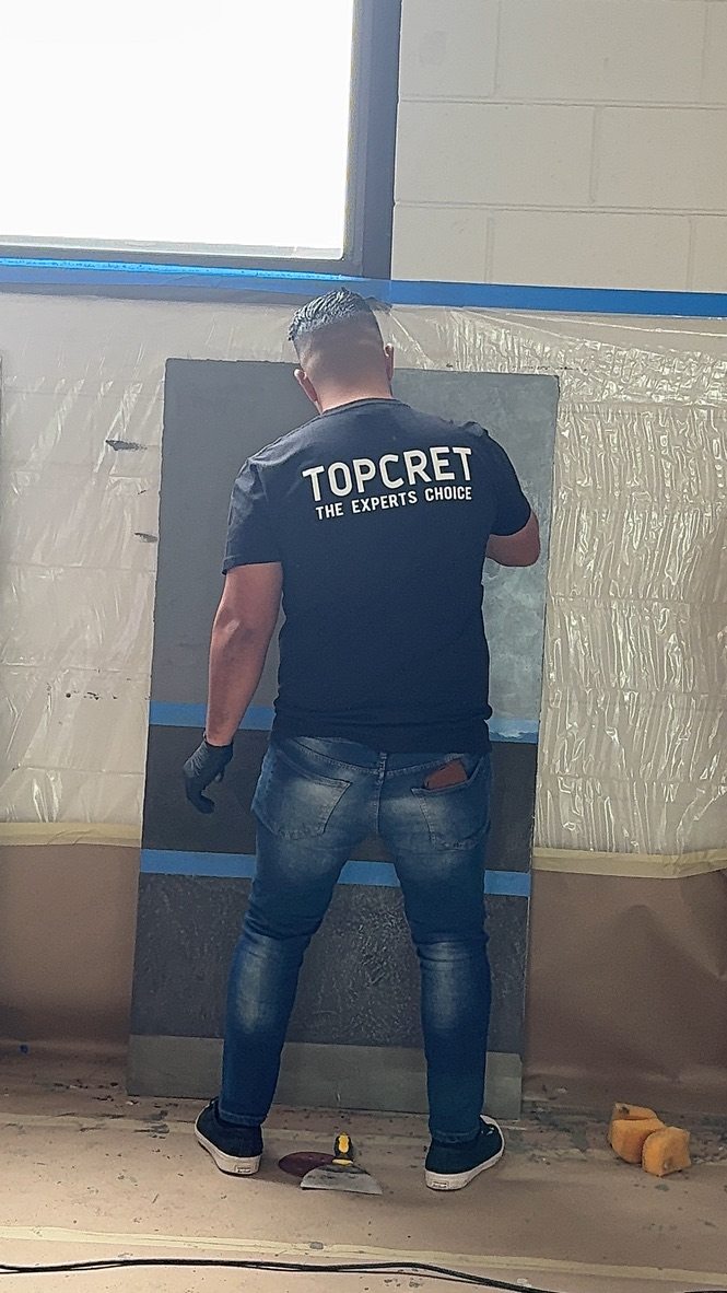 Applicator hand-troweling microcement on a sample board during training